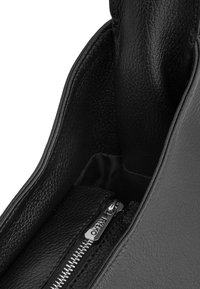 Juodas odinis rankinukas su tekstūruota išore ir sidabriniu užtrauktuku. Vidus išklotas audiniu, turi užtrauktuku uždaromą kišenę organizavimui.