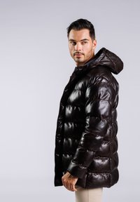 Chaqueta acolchada marrón de piel brillante con capucha, que presenta un diseño acolchado y un cierre frontal de cremallera.