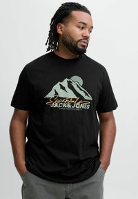 Sort bomulds t-shirt med et bjergmotiv i grøn og orange med teksten "Jack & Jones" og "Siden Nitten Halv" nedenfor.
