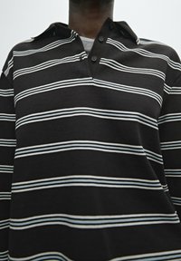 Black striped polo shirt featuring horizontal white and light blue stripes, with a two-button placket and a collar design.