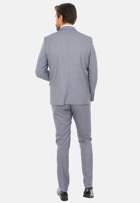 Completo grigio chiaro a due pezzi con giacca strutturata e pantaloni slim-fit. Tessuto morbido con una leggera trama, vestibilità su misura e rever a punta separati.