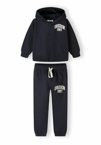 Marinblå hoodie och joggers-set, med framdragkedja, två fickor och "OREGON 1997" broderat i vitt på båda plagg.