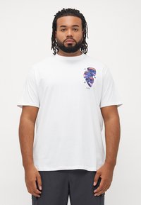 Hvid bomulds t-shirt med et flerfarvet grafisk tryk på venstre side. Rund hals, korte ærmer og en afslappet pasform.