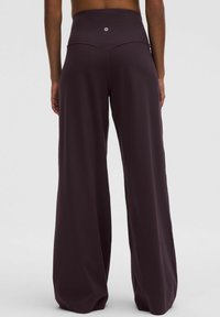 Verenon lahkeet tumman violetista kankaasta, jossa on korkea vyötärö. Takana on huomaamaton logo, ja kangas on sileä ilman näkyviä kuvioita.