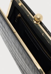 Μαύρη δερμάτινη τσάντα clutch με υφή κροκοδύλου, μεταλλικό κλείσιμο χρυσού τόνου, εσωτερική τσέπη με φερμουάρ και αφαίρεση μαύρης φόδρας.