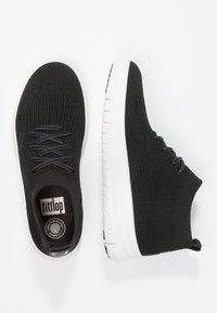 Zwarte gebreide sneakers met een gestructureerde bovenkant, zwarte veters en een witte zool. Voorzien van een treklipje en een gevoerde inlegzool met het merksymbool.