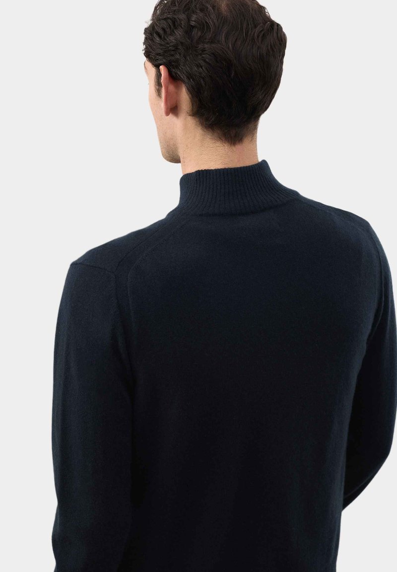 Maglione a maglia blu navy con colletto alto a coste e maniche lunghe, caratterizzato da una texture liscia e un design aderente per un look moderno.