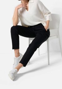 Czarne dopasowane spodnie z miękkiego materiału, o prostym kroju nogawek. Zestawione z białą swetrową bluzką i białymi trampkami. Minimalistyczny design.