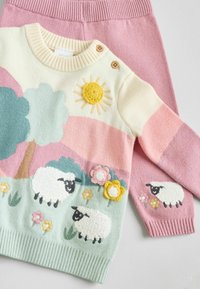 Sweter z dzianiny w pastelowych kolorach, z motywem owiec, kwiatów, słońca i drzewa. W zestawie z różowymi dzianinowymi spodniami. Zawiera teksturowane akcenty.