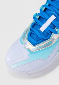 Ανοιχτό μπλε αθλητικό παπούτσι με υφή στο πάνω μέρος, έντονα μπλε κορδόνια σε αντίθεση, ι ριδίζουσες λεπτομέρειες και χαρακτηριστικό σχέδιο στη σόλα.