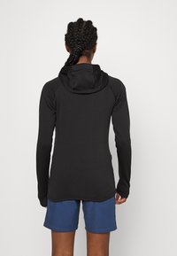 Sudadera negra de manga larga con un diseño ajustado y capucha ajustable, combinada con pantalones cortos azules. Textura suave con detalles en las costuras.