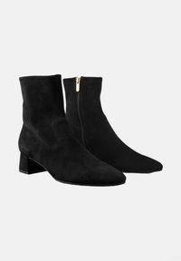 Bottines en suède noir avec un bout pointu et un petit talon bloc. Équipées d'une fermeture éclair sur le côté avec un accent doré pour un enfilage facile.