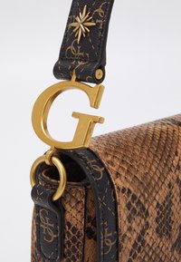 Ruskea pythonselkätasku, jossa on musta hihna, kultainen G-kirjainkoru ja kultaisia tähtiä hihnassa.