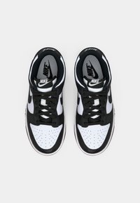 Melnā un baltā krāsā Nike sporta apavi ar perforētu purngala daļu, mīkstu apkaklīti un kontrastējošiem logotipiem uz mēles un sānus.