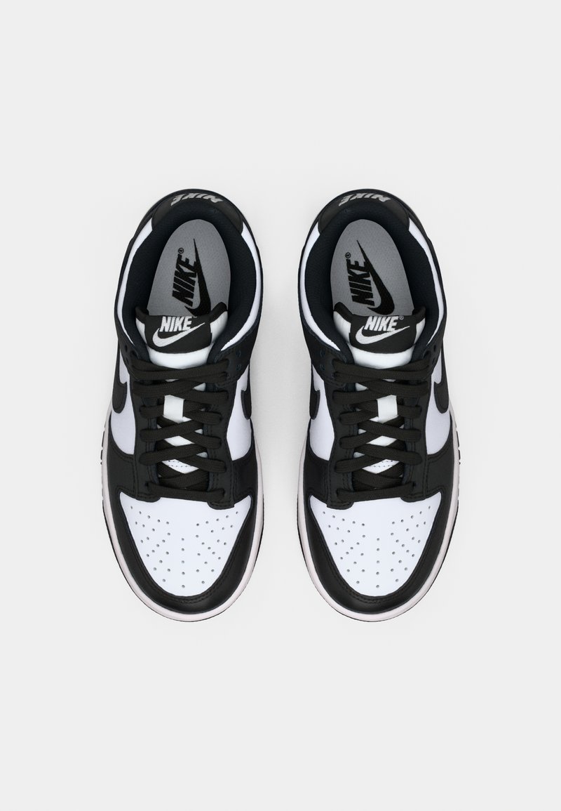 Las zapatillas Nike en blanco y negro cuentan con una caja de dedos perforada, un cuello acolchado y logotipos contrastantes en la lengüeta y el costado.