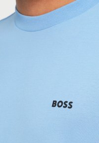 Ανοιχτό μπλε κοντομάνικο μπλουζάκι από απαλό ύφασμα, με μαύρο λογότυπο "BOSS" στο στήθος και ριμπ λαιμόκοψη.