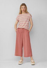 Gestreept T-shirt met korte mouwen in roze en wit, gecombineerd met losse, gestructureerde rustkleurige broeken. Heeft voorzakken en een verstelbare tailleband.