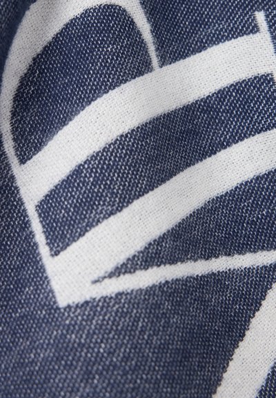 Gros plan sur un tissu bleu avec des formes géométriques blanches et une texture tissée visible.