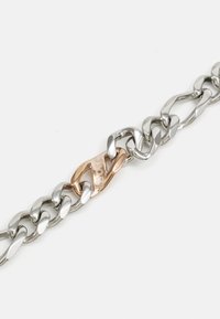 Bracelet en chaîne en argent et or rose avec des maillons lisses et arrondis, ainsi qu'un fermoir distinctif avec un détail de marque.