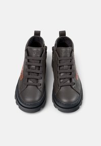 Scarpe in pelle grigia con finitura texturizzata, caratterizzate da dettagli in logo arancione, punta rotonda, design con lacci e una spessa suola in gomma nera.