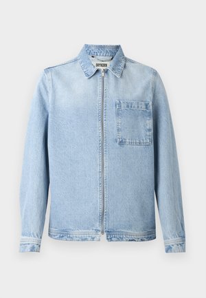Lys blå denimjakke med glidelås, krage, lange ermer, og brystlomme. Har en lett falmet tekstur og standard mansjetter.