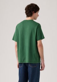 Zelené bavlněné tričko s krátkým rukávem, přímého střihu a kulatým výstřihem. Má jednoduchý design bez vzorů nebo akcentů.