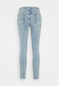 Vaqueros de denim de color azul claro con un corte ajustado, que cuentan con dos bolsillos traseros y detalles de costura. El tejido tiene una ligera textura y un acabado suave.