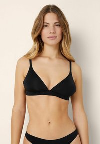 Black bra with a v-neck design, thin adjustable straps, and soft fabric. Features a seamless finish for smooth appearance.