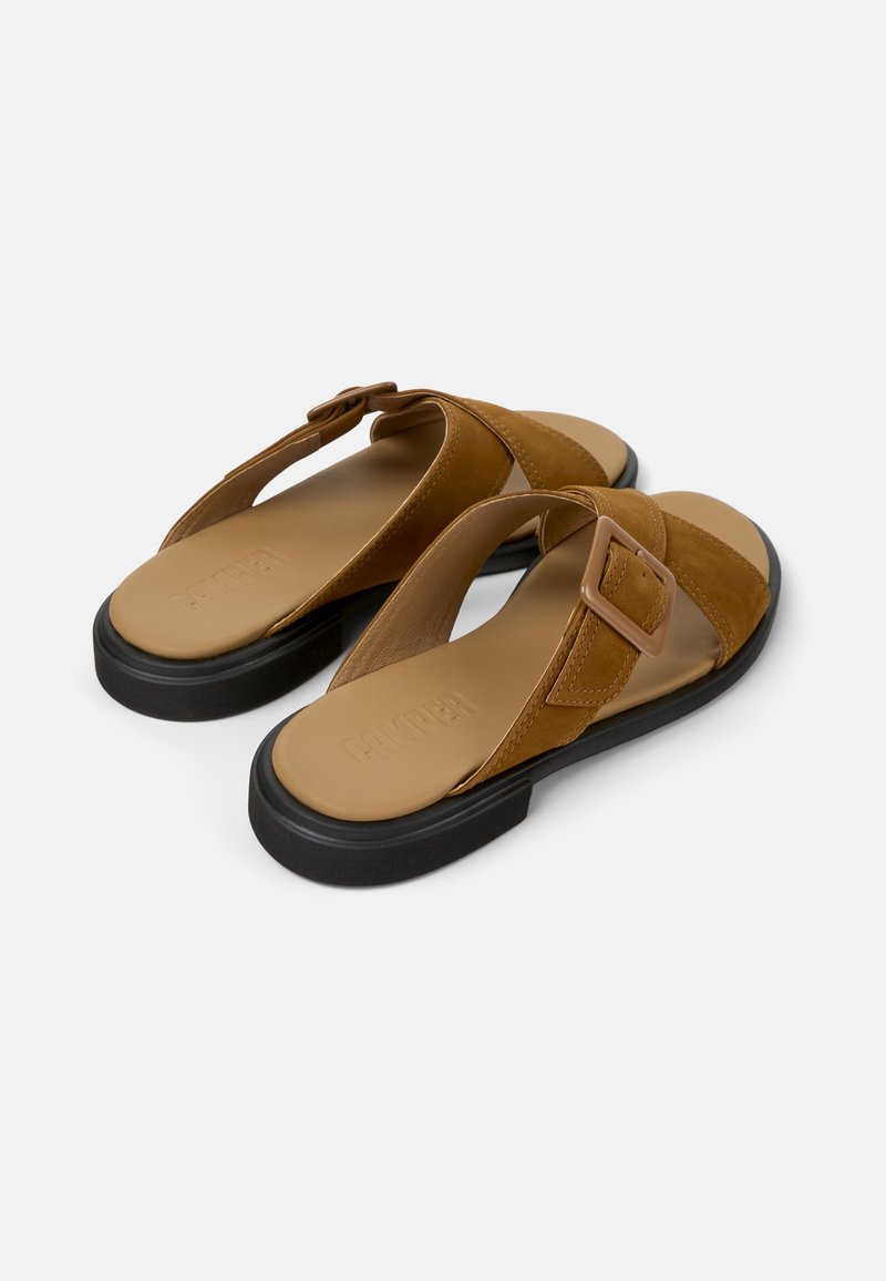 Sandalias de cuero marrón con correa ajustable, plantilla ancha y suela de goma negra. Presentan una textura suave y un detalle de hebilla cuadrada.