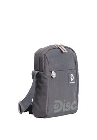 Kompakte graue Umhängetasche mit vorderer Reißverschlusstasche, verstellbarem Riemen und Discovery-Logo auf der Frontseite.