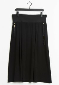 Musta hame, joka on valmistettu pehmeästä materiaalista. Siinä on ribbineulosvyötärö, kaksi vetoketjullista taskua kultaisilla yksityiskohdilla sekä ilmava, laskostettu malli.