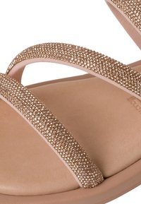 Sandali rosa oro con due cinturini testurizzati coperti di piccoli strass luccicanti, montati su una suola liscia di color marrone chiaro.