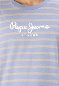 Prugasta majica u svijetloplavoj i bež boji, s okruglim izrezom i bijelim logotipom "Pepe Jeans London" na prsima. Mekana tkanina.