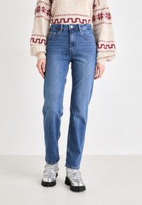 Απαλά μπλε ψηλόμεσα τζιν παντελόνια με ευθεία πόδια, φτιαγμένα από τζιν. Διαθέτουν κλασικό σχέδιο πέντε τσέπης και διακριτική φθορά στο ύφασμα.