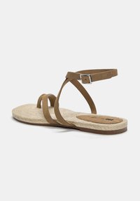 Bruine suède sandaal met drie dunne banden en een verstelbare enkelband. Espadrille-stijl jute zool met een vlak voetbed.