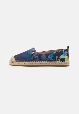 Espadrille bleu marine à fleurs, modèle slip-on, avec semelle en jute et petit logo doré sur le côté, vue de profil sur fond blanc.
