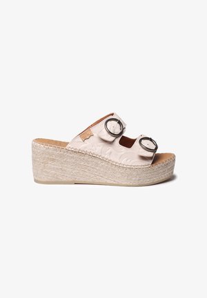 Šviesiai rudos platformos sandaidai su dviem reguliuojamais dirželiais, apvaliomis juodomis sagtimis ir pynėmis jūroje pagaminta platforma. Lygus, iškilmingas viršutinio dizaino paviršius.