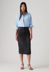 Light blue button-up shirt with rolled sleeves, paired with a high-waisted black denim skirt. Smooth texture, knee-length design.