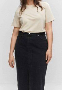 Béžové bavlněné tričko s krátkými rukávy v kombinaci s černou džínovou sukní s vysokým pasem, předním rozparkem a zadními kapsami.