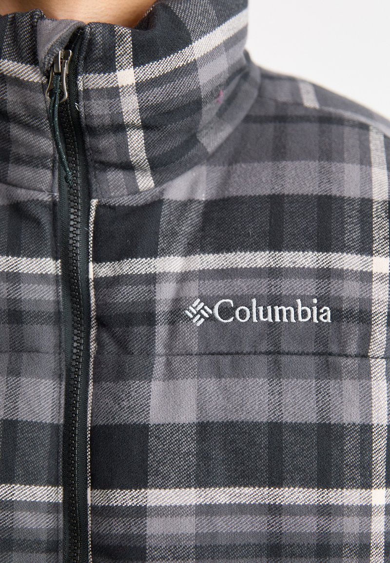Szara kurtka zapinana na zamek z wysokim kołnierzem, ozdobiona czarno-białymi wzorami oraz małym logo Columbii na lewej stronie klatki piersiowej.