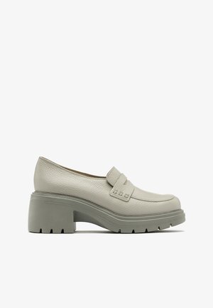 Mocassin gris clair à talon épais, empeigne en cuir texturé et semelle épaisse à relief, vue de côté sur fond blanc.