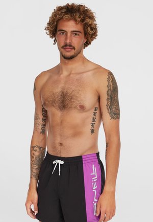 Schwarze Badehosen mit lila Akzenten und einer weißen Kordel. Der Stoff ist glatt, und auf den Armen des Modells sind sichtbare Tattoos.