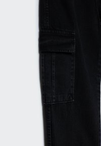 Pantaloni cargo neri con una tasca laterale, che mostrano dettagli di trama e cuciture su uno sfondo grigio chiaro.