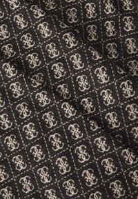 Sort stof med et gentaget hvidt logo-mønster, der har en tekstureret overflade og subtile variationer i trådtj thickness.