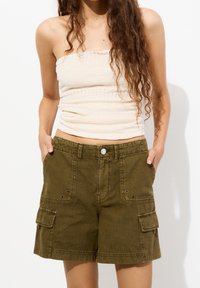 Pantaloni cargo verde oliva con vestibilità rilassata, dotati di due tasche frontali e due tasche laterali, realizzati in un tessuto morbido e texturizzato.