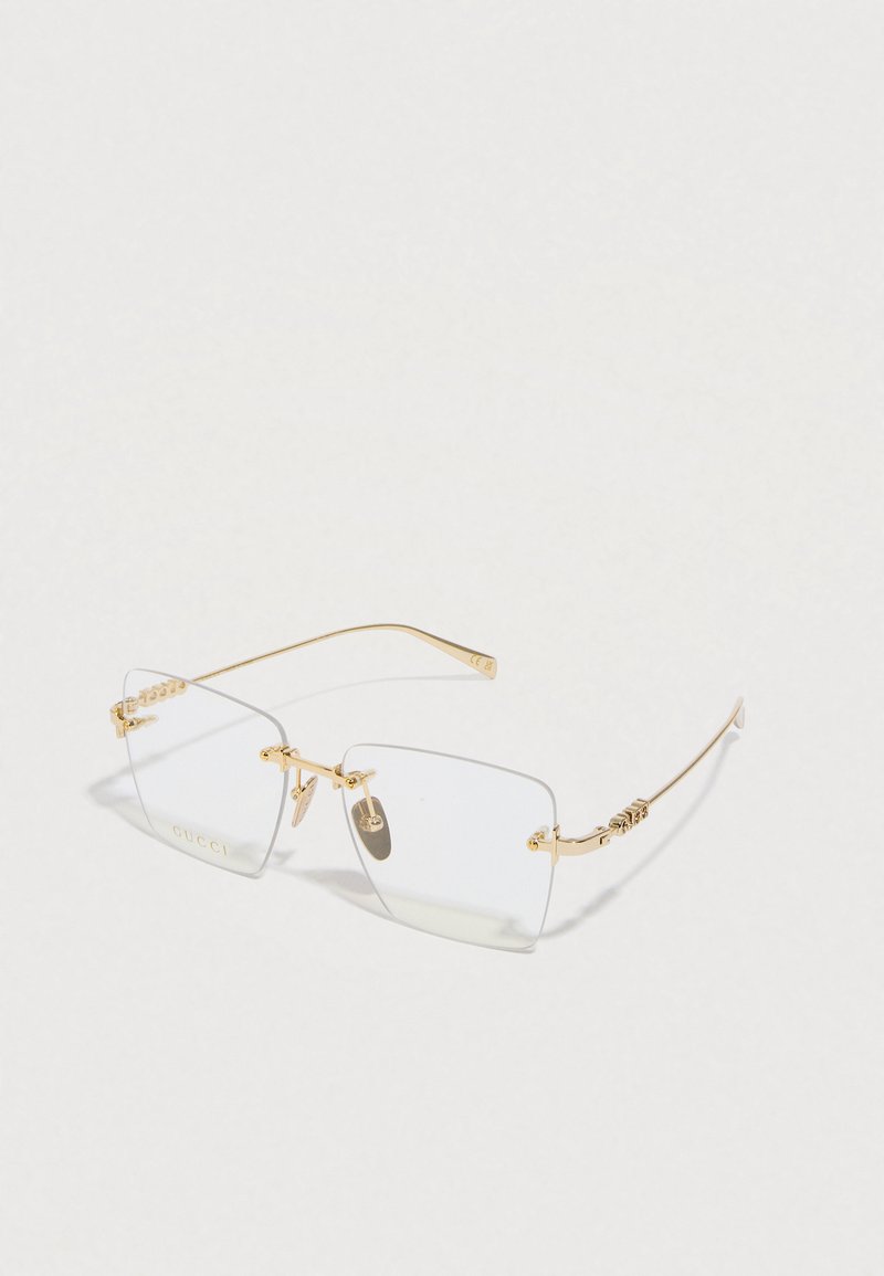 Aranyfém napszemüveg téglalap alakú, átlátszó lencsékkel, díszítő elemekkel a szárakon és a "GUCCI" logóval. Minimalista dizájn, elegáns forma.