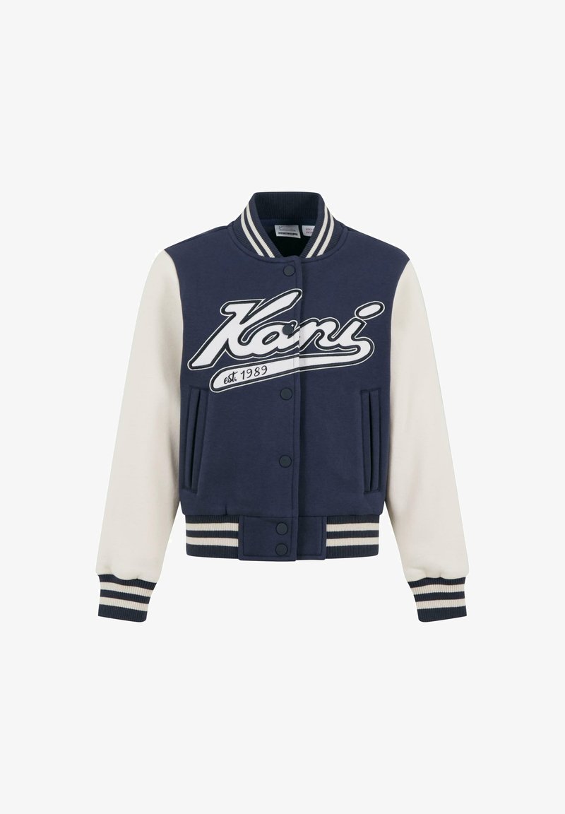 Tumesinine ülikoolijaki disain, millel on valged varrukad, soonikust mansetid ja vöökoht. Looje suur valge logo ja asutamise aasta trükk. Ees on taskud.