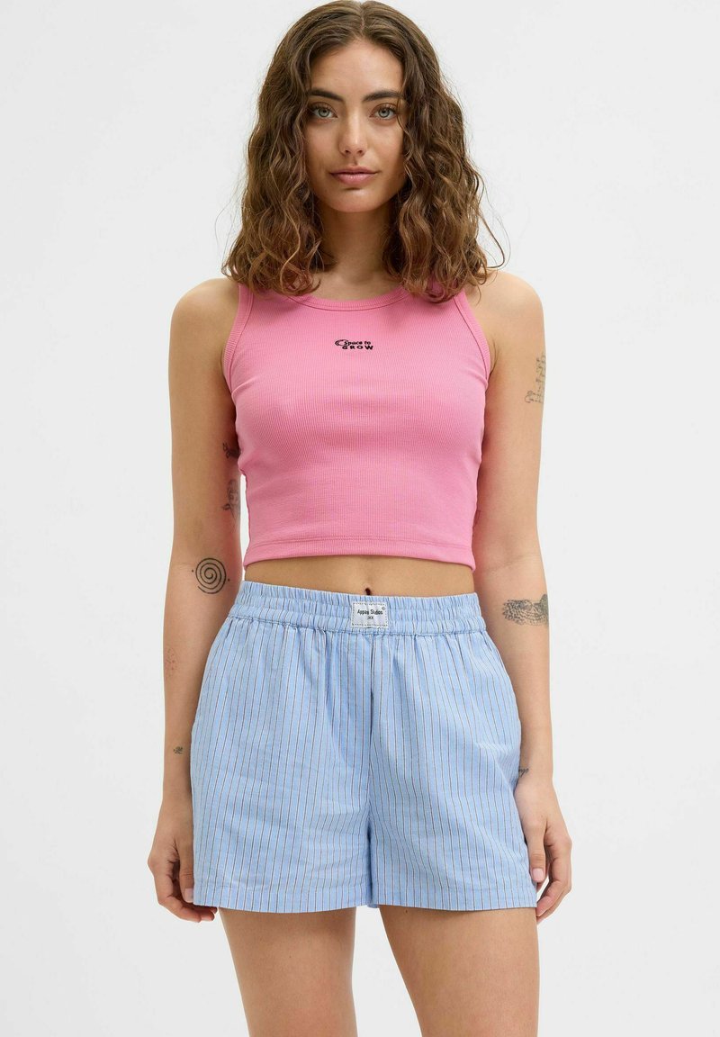 Roza rebrasta kratka majica s črnim logotipom in svetloplavimi kratkimi hlačami z elastičnim pasom; sproščen outfit s prostim krojem.