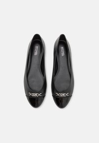 Zwarte leren balletschoenen met een ronde neus, glanzende lakaccenten en een zilveren kettingdetail aan de voorkant. Gladde textuur overal.
