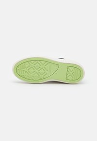 Biała podeszwa sneakerów z teksturowaną, zieloną gumową dolną częścią. Oferuje wzór diamentowy dla lepszej przyczepności oraz wyryty detal logo marki.
